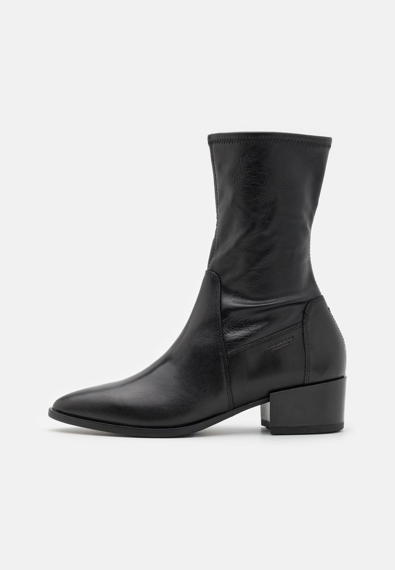 Bottine noire à cheville avec un bout pointu élégant, en cuir lisse. Dotée d'un petit talon carré et d'un design minimaliste sans aucune pièce métallique visible.