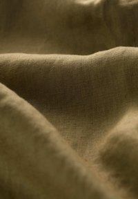 Textured, olive green fabric with a slightly wrinkled surface, showcasing a natural, woven appearance and subtle variations in shade.