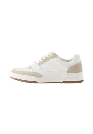 Zapatilla blanca de corte bajo con detalles en ante beige, cordones blancos, parte superior texturizada y suela de goma marrón, mostrada desde el lado izquierdo.