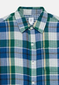 Chemise à manches courtes en tissu à carreaux présentant un motif à damier bleu, vert et jaune, avec un devant à boutons et une poche sur la poitrine. Fabriquée en tissu léger.