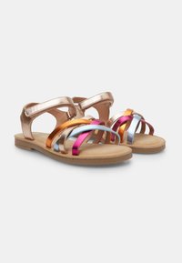 Metallisch rose goldene Sandalen mit mehreren bunten Riemen in Orange, Pink, Blau und Silber. Flache Sohle mit weicher Textur. Verstellbarer Knöchelriemen.