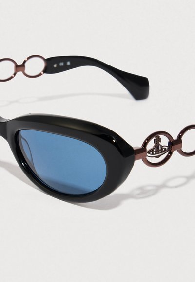 Gafas de sol negras con lentes azules, montura gruesa y acentos metálicos marrones en las patillas. Acabado brillante, forma redondeada.