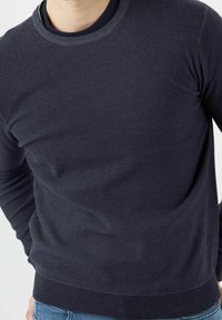 Dunkelblauer Pullover mit Rundhalsausschnitt aus weichem, strukturiertem Strick. Verfügt über gerippte Bündchen und Saum für eine figurbetonte Silhouette.