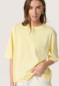 Tricou galben cu mânecă scurtă din bumbac moale, cu o croială lejeră, decolteu rotund și textură subtilă. Fără modele sau accente proeminente.