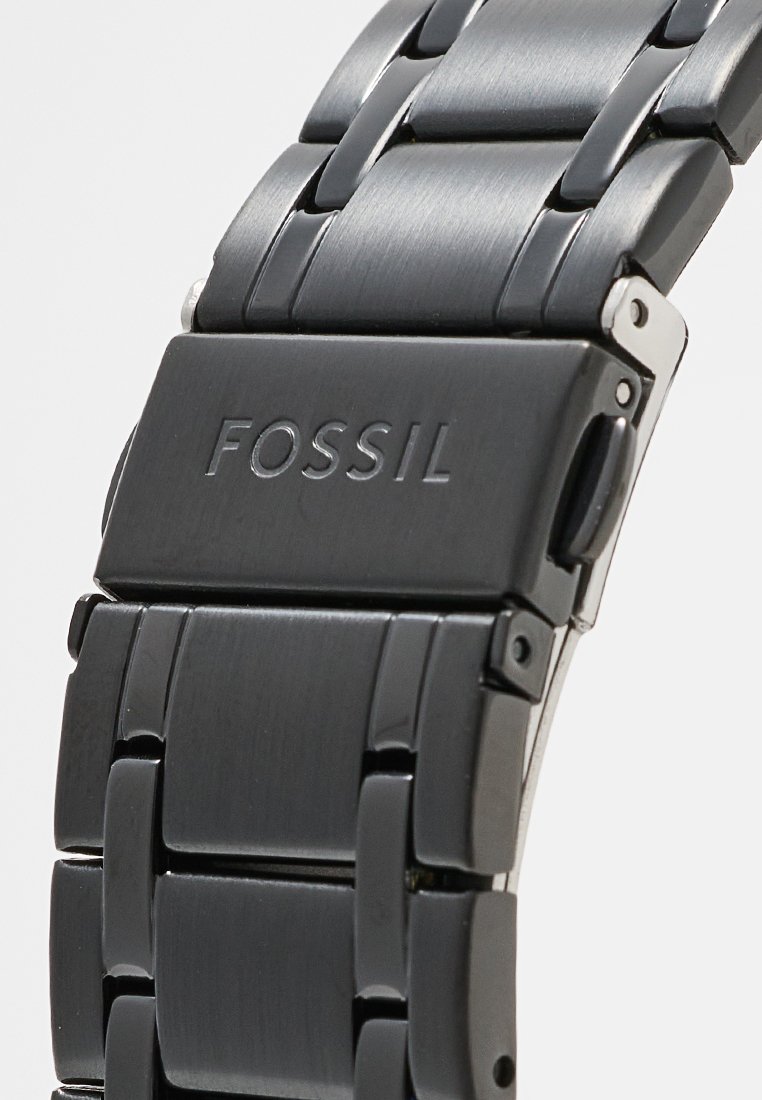 Schwarzes Metallarmband mit eleganten Gliedern und einem polierten Verschluss. Mit eingraviertem "FOSSIL"-Logo auf dem Verschluss. Glatte, matte Oberfläche im gesamten Design.
