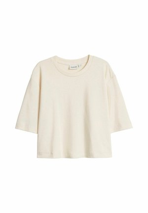 Kremowy, krótki rękaw, sweter o pudełkowym kroju z okrągłym dekoltem i widoczną metką marki wewnątrz kołnierza.