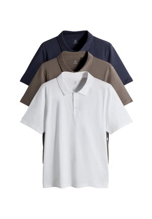 Trois polos empilés : blanc, marron et bleu marine. Manches courtes, col à revers, tissu lisse et léger. Design simple.
