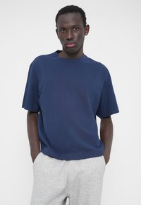 Μπλούζα σε ναυτικό μπλε με κοντά μανίκια από απαλό βαμβάκι, με άνετη εφαρμογή και στρογγυλή λαιμόκοψη, σε συνδυασμό με γκρι φόρμα