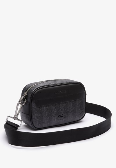 Sac bandoulière noir avec surface texturée, motif géométrique, fermeture éclair et sangle réglable. Présente un logo sur le panneau avant et sur le côté.