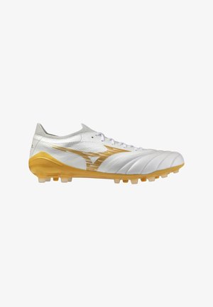 Chaussure de football blanche et dorée avec lacets, tige texturée et crampons moulés pour jouer sur terrain ferme, montrée de profil droit.