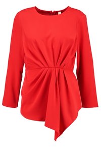 Rød top med lange ærmer, rund udskæring og samlet design ved taljen, featuring en draperet front og asymmetrisk kant. Glat stoftekstur.