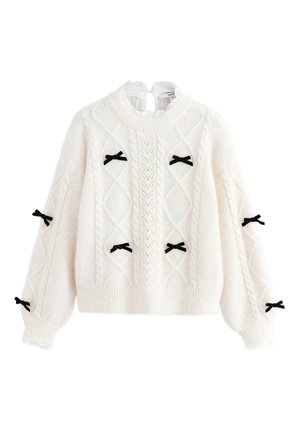 Krém színű kötött pulóver texturált mintával, fekete bársonyszalagokkal az ujján, bordázott szegéllyel és mandzsettákkal.