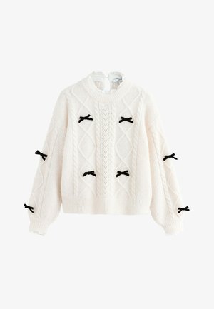 Pull en maille crème avec un motif texturé, arborant des nœuds en velours noir sur les manches et une bordure côtelée aux poignets et à l'ourlet.