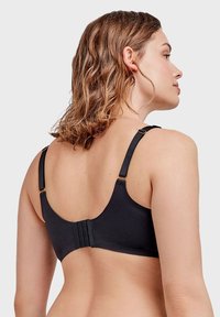 Soutien-gorge noir avec des bretelles réglables, fermeture à crochet et œillet, tissu lisse et design de dos arrondi. Présente des accents en métal doré.