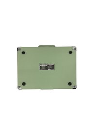 Exterior verde y texturizado, acentos metálicos en las esquinas, asa robusta y pies de goma. Incluye una etiqueta de precaución y una placa de marca en la parte inferior.