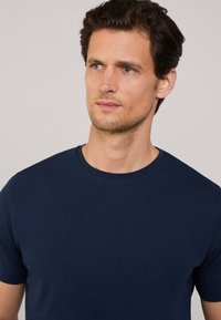 T-shirt bleu marine à manches courtes en tissu doux avec un col rond, présentant une texture lisse et une coupe classique.