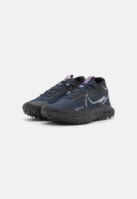 Zapatillas de correr con parte superior de malla azul marino, suela de goma negra y acentos de cordones morados; cuentan con una etiqueta GORE-TEX para impermeabilidad.