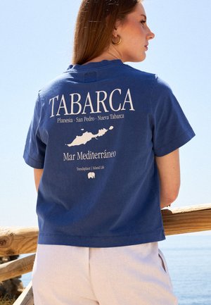 Camiseta de algodón azul con el texto "TABARCA", un mapa de la isla y la impresión "Mar Mediterráneo" en la parte posterior; de mangas cortas, ajuste relajado.