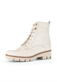 Beige leren enkelboot met een ronde neus, vetersluiting aan de voorkant, metalen oogjes, en een chunky beige zool met noppen voor grip.