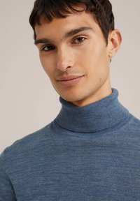 Blå polotröja i mjukt stickat material, med en figursydd design och ribbad krage. Slät struktur med små färgvariationer.