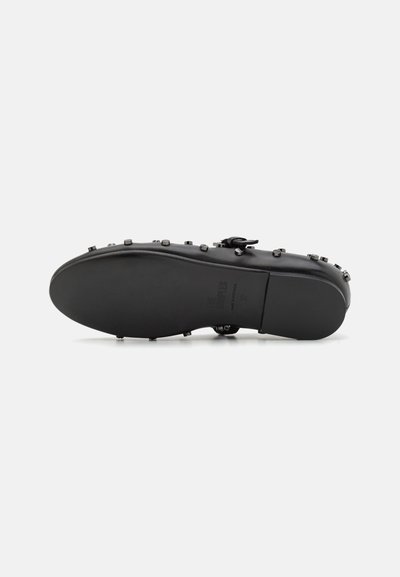 Semelle de chaussure en cuir noir avec une texture lisse, ornée de clous décoratifs sur le côté et présentant un design légèrement courbé.