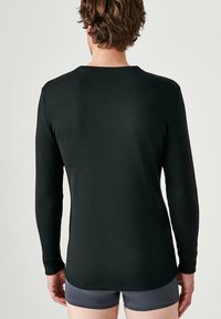 Maglietta nera a maniche lunghe in cotone morbido ed elastico. Collo rotondo e design aderente con una texture liscia. Senza motivi o accenti visibili.