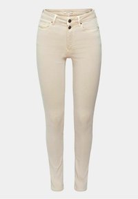 Jeans skinny beige con tiro alto, hechos de denim. Presenta dos bolsillos frontales, dos bolsillos traseros y dos botones negros en la cintura.