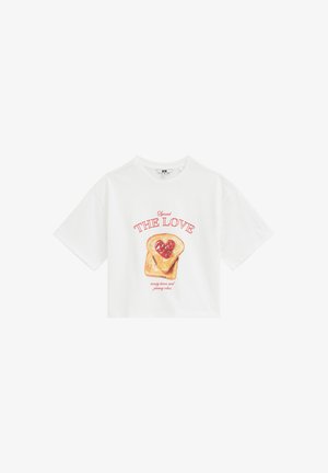 Hvid T-shirt med korte ærmer med grafik af toast med et hjerteformet rødt syltetøj og teksten "Spread The Love" i rødt bogstav.