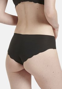 Biancheria intima nera con bordo scallop, realizzata in tessuto morbido, caratterizzata da un taglio a mezz' altezza e un design minimalista; texture uniforme e senza branding visibile.