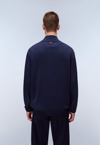 Dunkelblauer Pullover mit Kragen, gerippten Bündchen und lockerer Passform. Mit leichtem Stitching an den Schultern und einem kleinen Logodetail auf der Rückseite.