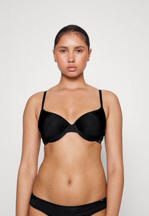 Black padded bra with smooth fabric, adjustable straps, and a curved shape. The design features a seamless finish for comfort.