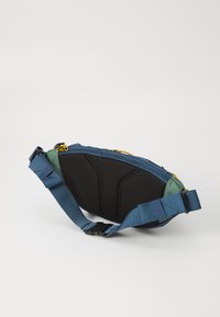 Borsa a tracolla blu e verde con pannello nero testurizzato, tracolla regolabile, cerniera gialla e design compatto e angolato per la portabilità.