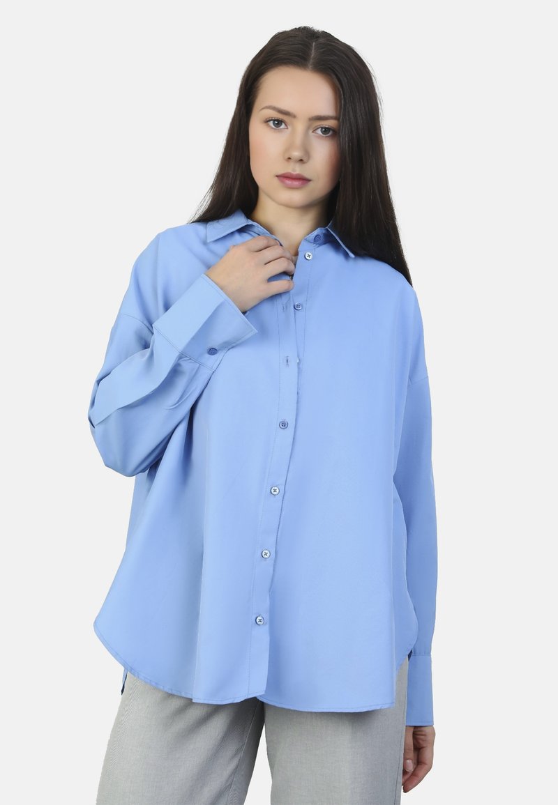 Camicia a maniche lunghe azzurro chiaro con chiusura a bottoni, colletto e leggera lucentezza. Presenta una vestibilità rilassata e un orlo curvo.