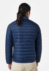 Marinblå, quiltad pufferjacka med ståkrage. Tillverkad av slät, vattenavvisande material. Elastisk nederkant och diskreta sidofickor.