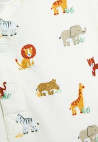 Tissu blanc doux avec de petits animaux de dessin animé colorés, notamment un lion, un éléphant, une girafe, un zèbre, un rhinocéros et un tigre, ainsi que des boutons-pression le long d'un bord.