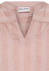 Blouse rose clair à rayures blanches verticales, un large col rond avec une découpe en V centrale, et une étiquette Pulz Jeans à l'intérieur du col.