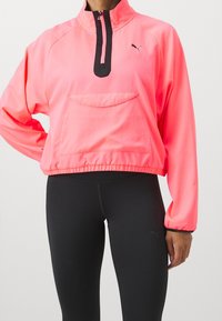 Kevyt, vetoketjullinen takki kirkkaan vaaleanpunaisena, jossa on puolivälin vetoketju, mustia yksityiskohtia ja etutasku. Pehmeä rakenne, urheilullinen istuvuus.