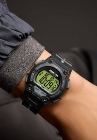 Digital Timex Ironman watch with a black rubber strap, green LCD display, buttons labeled "SET," "SPLIT," and "STOP/RESET," 200m water resistance.