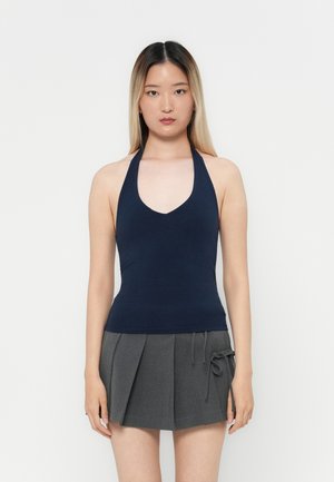 Haut à col halter bleu marine avec un décolleté en V profond et une coupe ajustée, associé à une mini-jupe plissée grise avec un détail à cordon.