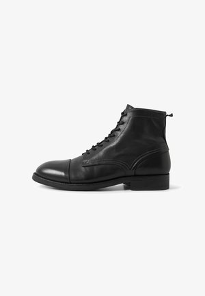 Black leather ankle boots with a smooth finish, round toe, lace-up design, and decorative stitching on the sides. Flat rubber sole.