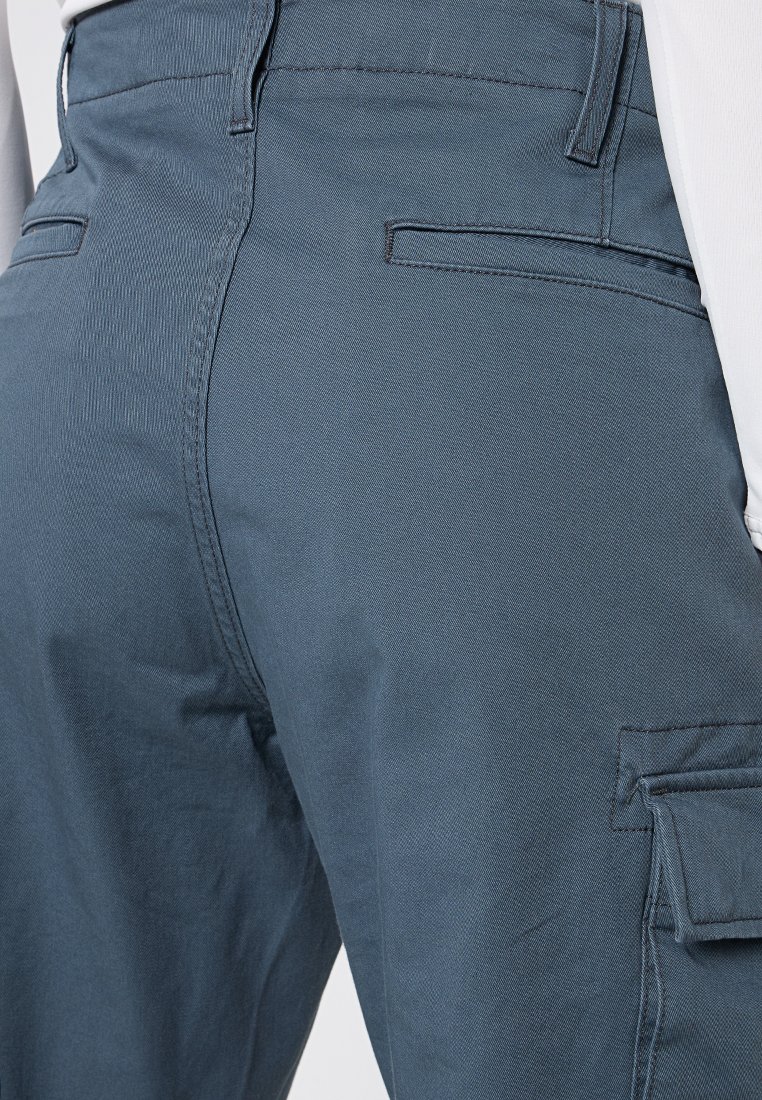 Cargo-Hosen in einem gedämpften Blauton, aus strukturiertem Stoff, mit mehreren Taschen und einem taillierten Design, das sich zum Knöchel hin verjüngt.