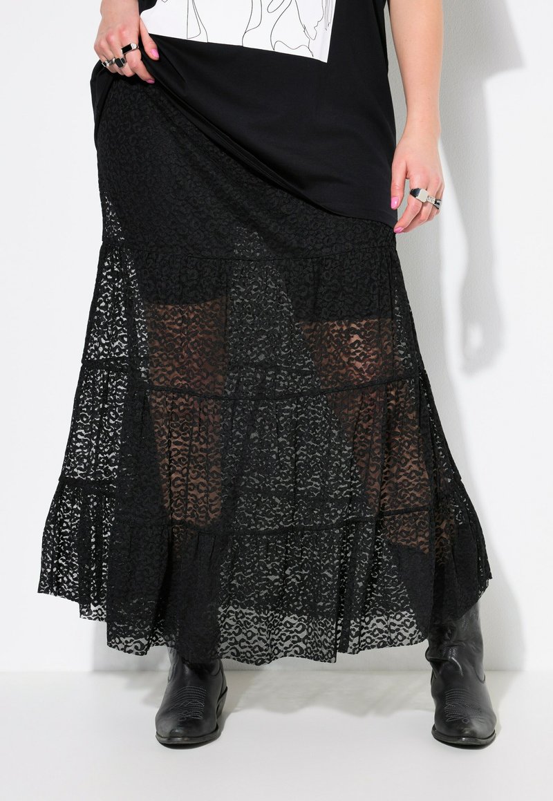 Schwarzer Spitzen-Maxi-Rock mit gestuftem Design, durchscheinendem Überwurf, kompliziertem Muster und Rüsche am Saum, kombiniert mit schwarzen Stiefeletten.