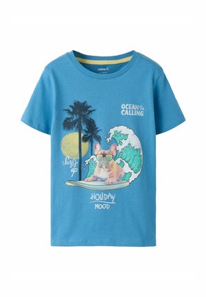 Sinine T-särk, mille peal on graafika Prantsuse bulldogist päikeseprillidega surfilaudal, palmipuud, lained, päike ja tekst "Ocean is Calling", "Holiday Mood".