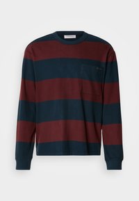 Μπλούζα με μακρύ μανίκι και ρίγες σε ναυτικό μπλε και μπορντό, με λαιμόκοψη και τσέπη στο στήθος με διακριτική λεπτομέρεια λογότυπου. Κατασκευασμένη από βαμβάκι.