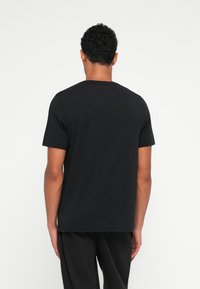 Μαύρο κοντομάνι�κο μπλουζάκι από βαμβάκι, με στρογγυλή λαιμόκοψη και κανονική εφαρμογή. Απαλή υφή, χωρίς εμφανή σχέδια ή διακοσμήσεις.