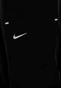 Crne Nike kratke hlače s istaknutim srebrnim logom, velikom preklopnom džepom i glatkom, teksturiranom tkaninom s aerodinamičnim dizajnom.