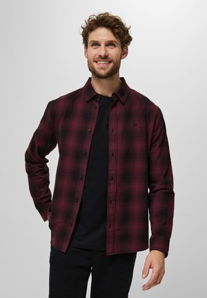 Camisa de cuadros de manga larga en burdeos y negro, con un botón frontal y tejido suave con un ajuste relajado. Camiseta negra visible.