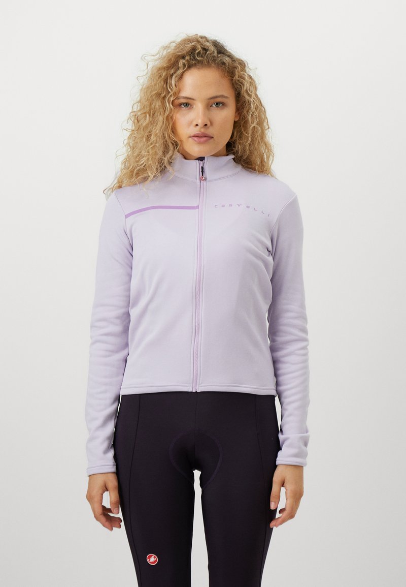 Svetlestrofialová dlhá bunda na zips z mäkkého materiálu, vybavená vyšitým logom a vysokým golierom, v kombinácii s čiernymi cyklistickými šortkami.
