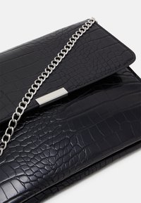 Svart clutchväska i syntetisk läder med krokodilstruktur, silverfärgad kedjesnurra och metallisk lås, med en stilren och minimalistisk design.