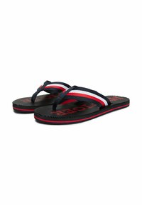 Sorte flip-flops med marineblå stropper, der har røde og hvide striber; ribbet sål med "HAST" tekst. Holdbart materiale til hverdagsslitage.